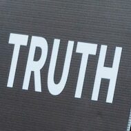 a man in a mask holding a sign that says truth